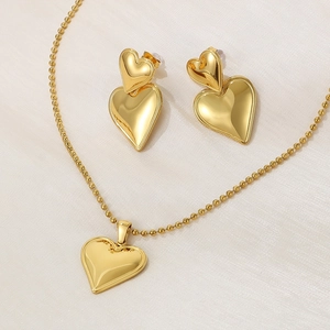 Close-up of golden heart jewelry set with necklace and earrings on silk background