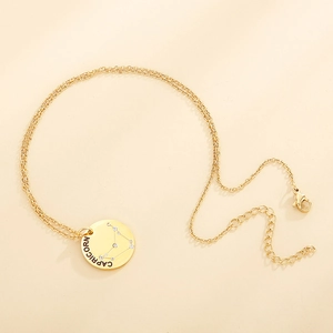 Detail of gold Capricorn constellation necklace with sparkling rhinestones on coin pendant
