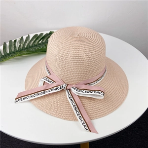 Vue détaillée de dessus d'un chapeau de paille rose avec ruban de satin et motif texturé