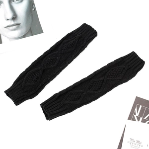 Close-up of black cable knit arm warmers with thick braided texture and elastic cuffs