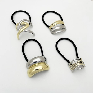 Detailed view of four geometric metal hair ties in polished gold and silver finishes