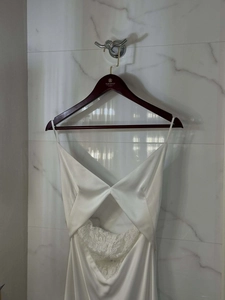 Detail of white satin dress featuring intricate lace patchwork and cutout design