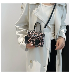 Detail shot of mini pink leopard print handbag with cute cartoon eyes and 3D hand charms