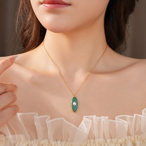 Detail of vintage gold necklace with sun motif oval green stone and pearl on model