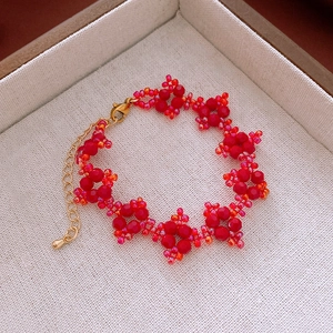 Détail du bracelet en perles de fleurs rouges avec fermoir doré sur boîte à bijoux