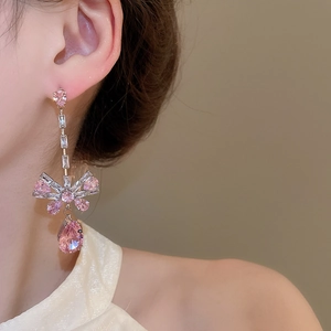 Detail of pink zircon bow tassel earrings worn by a model in soft natural lighting