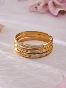 Vue détaillée de trois bracelets joncs dorés en acier inoxydable sertis de zircones