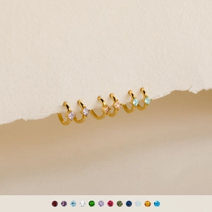 Elegant gold diamond-shaped earrings with colorful square gems on textured paper