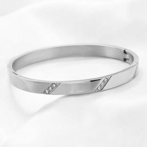 Detail of 6mm polished stainless steel bangle with slanted crystal accents on silk