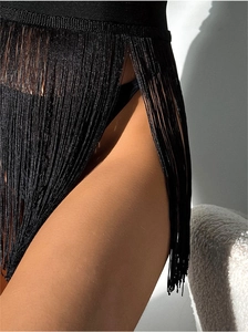 Detail of black fringe beach cover-up with high slit and textured tassels in soft lighting