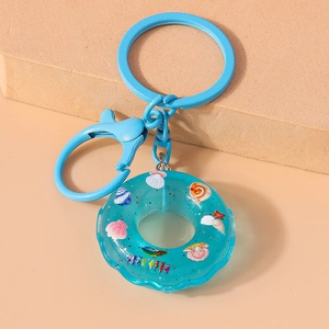 Blue donut resin keychain with colorful shells and pearls on a geometric prop