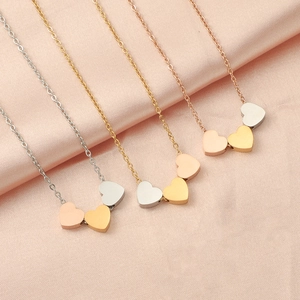 Three-color minimalist stainless steel heart pendant necklaces on pink silk background