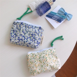 Detailed macro view of cotton floral mini pouches with green rope zippers on wood surface