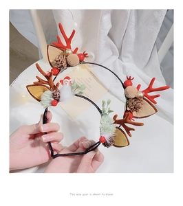 Close-up of reindeer antler headband with pine cones, berries, and plush ornaments