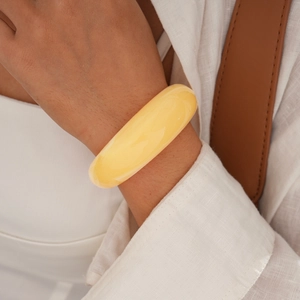 Close-up of minimalist yellow resin geometric bangle on woman's wrist for a chic look