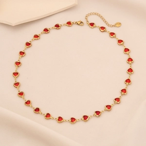 Close-up of heart-shaped gold necklace with red gemstones and lobster clasp detail