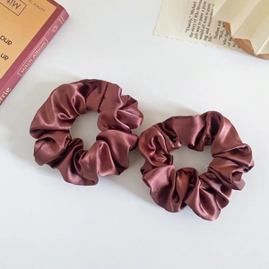 Close-up of two deep red floral leopard print silk scrunchies on a minimalist background