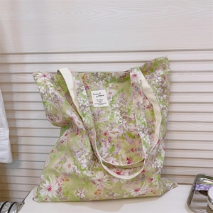Dettaglio della borsa tote in tela floreale verde con manici in cotone bianco