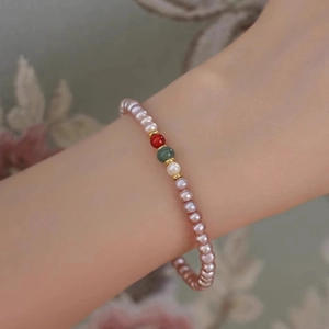 Detail of freshwater pearl bracelet with agate beads and gold spacers on woman's wrist