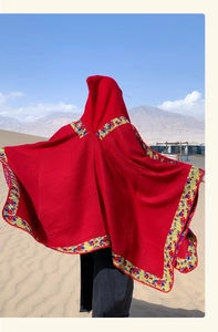 Detailed view of red ethnic hooded cloak with yellow embroidery in a desert landscape