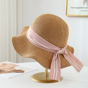 Minimalist straw knit sun hat for women featuring a stylish bow and wavy brim detail