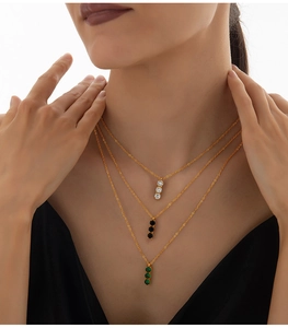 Detailed view of triple-layered gold necklace with white, black, and green zircons