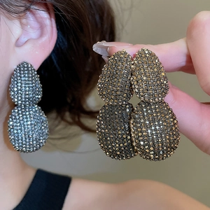 Detailed close-up of oval double-layered pavé-set earrings in silver and champagne gold