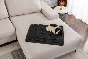 Quilted black pet furniture protectors in four sizes on a sofa with a dog model