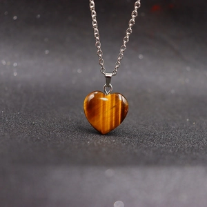 Natural tiger eye stone heart pendant necklace with silver chain on black background