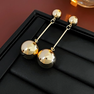 Detail of gold metal ball drop earrings featuring long tassels on a leather display