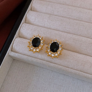 Close-up of vintage golden wing earrings with black oval gem and sparkling rhinestones
