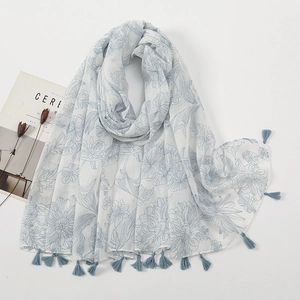 Detail of floral printed voile scarf with blue tassels and soft artistic patterns