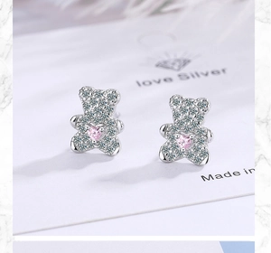 Macro view of silver bear stud earrings with crystal pave and pink heart gemstone