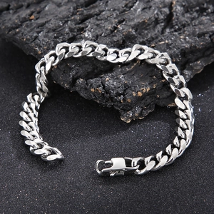 Polished silver stainless steel Cuban link bracelet with lobster clasp on dark stone background