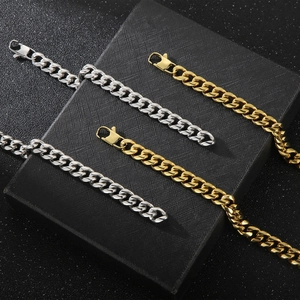 Polished gold and silver cuban link chain necklaces displayed on a black jewelry box