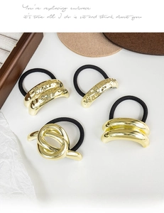 Detailed view of four golden textured metal elastic hair ties on minimalist background