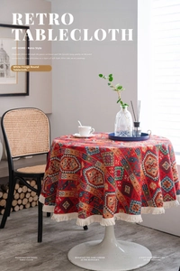 Close-up of retro red round tablecloth featuring geometric patterns and white cotton tassels