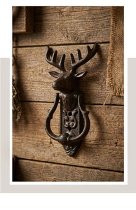 Detail of vintage cast iron deer head door knocker with rustic texture on wooden wall
