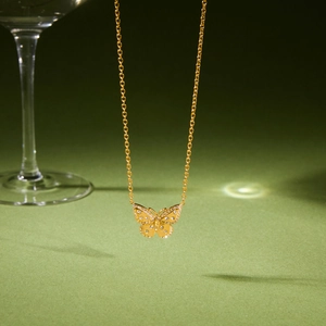 Détail d'un collier pendentif papillon doré avec incrustation de cristaux brillants