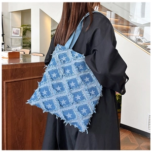 Detail of frayed edge denim patchwork tote bag featuring white star prints and retro style