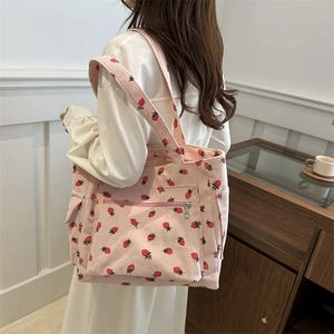 Pink corduroy tote bag with strawberry patterns featuring a front zipper pocket and strap