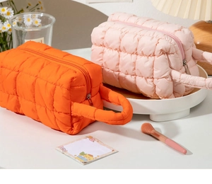 Detailed view of quilted makeup bags in vibrant orange and soft pink with sturdy handles