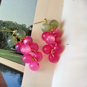 Détail de boucles d'oreilles grappes de raisin en résine rose sur pages de livre