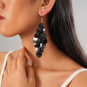 Dramatic black sequin tassel geometric earrings with gold hooks on a fashion model