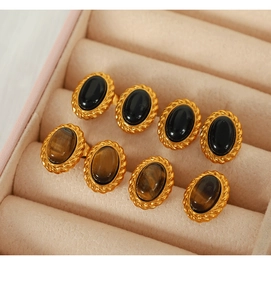Detailed close-up of vintage oval tiger eye stones and black gems in a pink velvet box