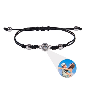 Macro detail of custom photo projection stone on black braided rope bracelet with steel beads