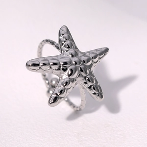 Macro detail of silver starfish ring featuring embossed grain texture and engraved band