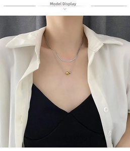 Close-up of double-layer necklace with gold and silver beads on a model wearing white