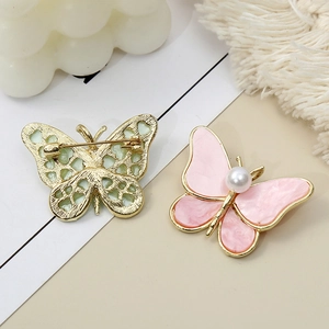 Elegant gold butterfly brooch with pink enamel wings and a centered pearl accent