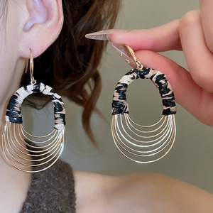 Detail view of oval tiered golden arc earrings with brown zebra pattern leather texture
